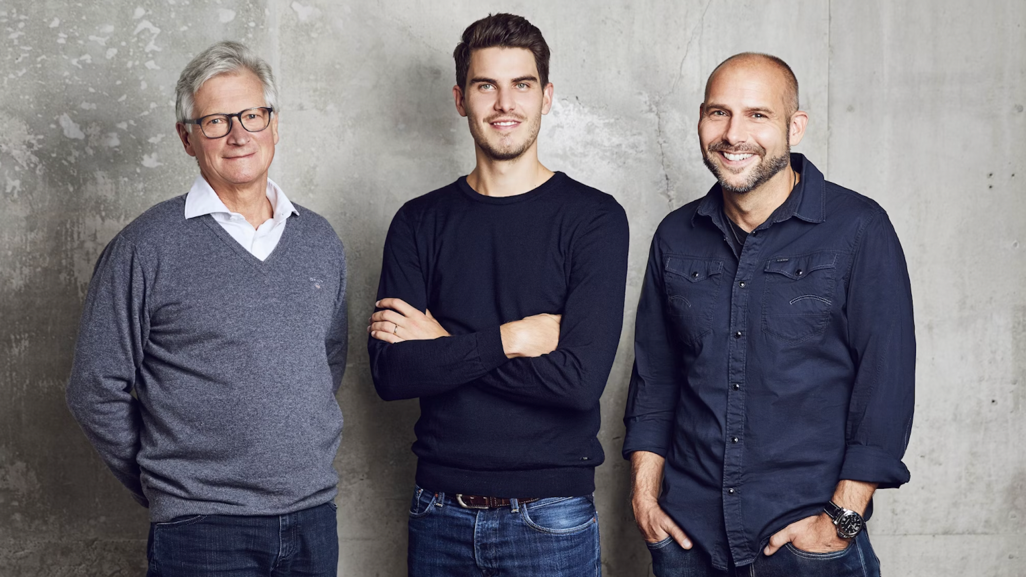 Drei Männer vor einer grauen Wand
