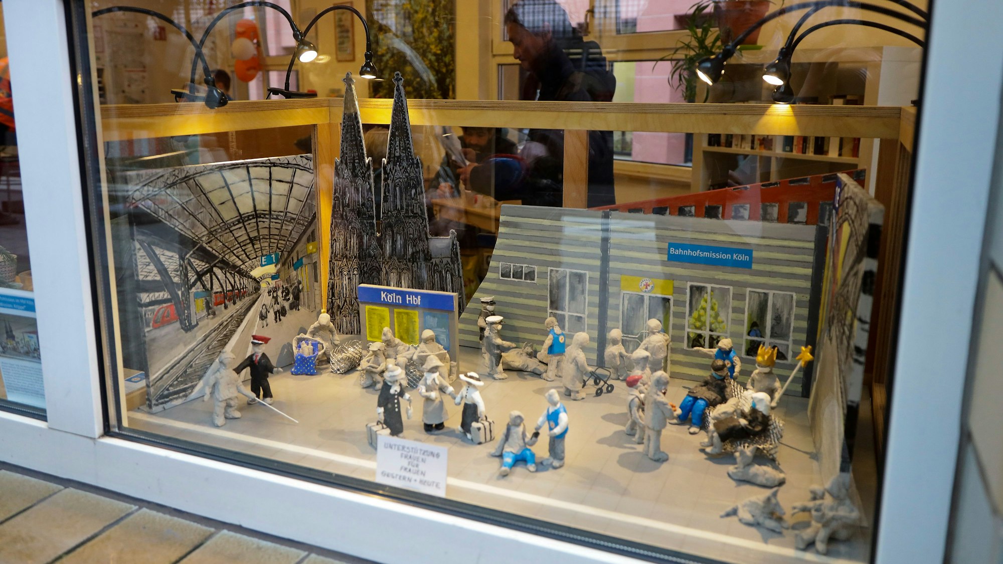 Krippe der Bahnhofsmission im Kölner Hauptbahnhof hinter einem Fenster.