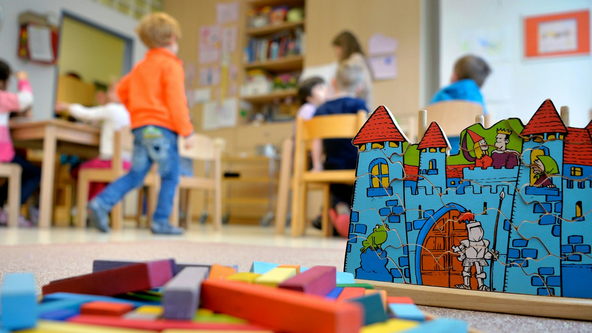 Zu sehen sind Kinder in einer Kindertagesstätte und Spielzeug.