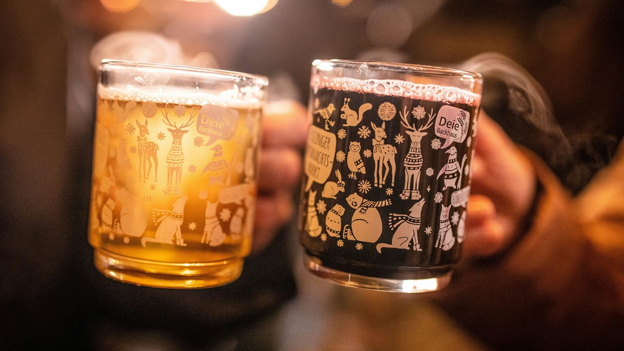 Man sieht zwei Hände, die zwei Tassen mit weißem und rotem Glühwein halten.