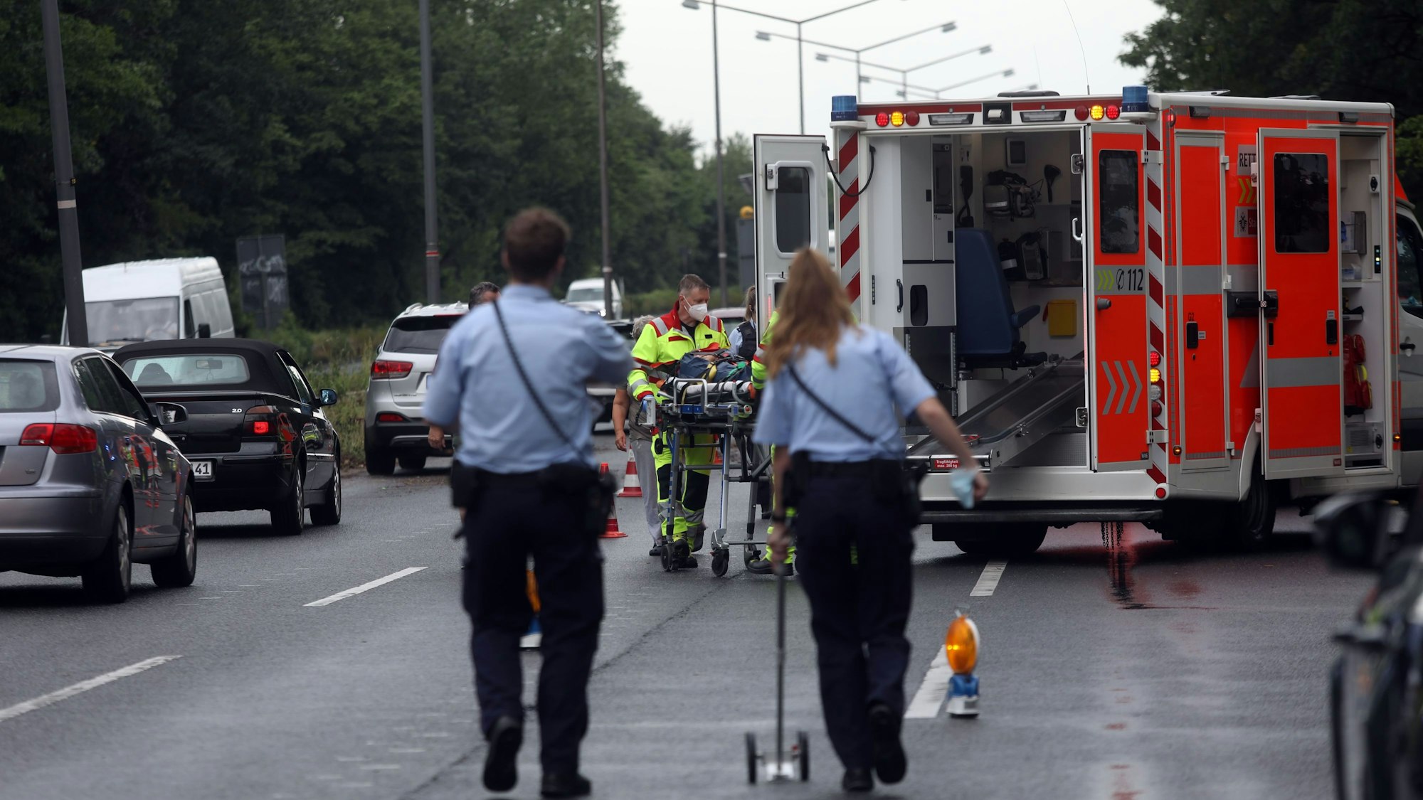 Polizisten und ein Rettungswagen stehen an einer Unfallstelle.