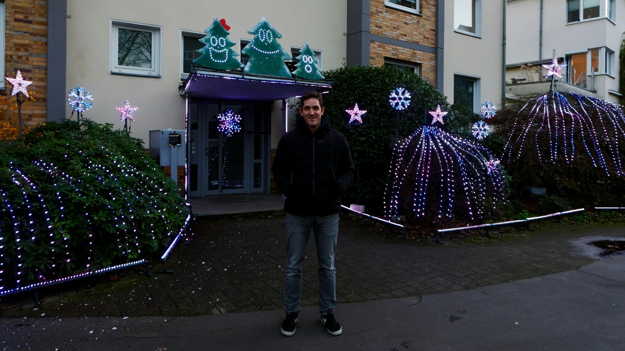 Simon Biela vor dem bunt blinkendem Eingangsbereich seines Wohnhauses.