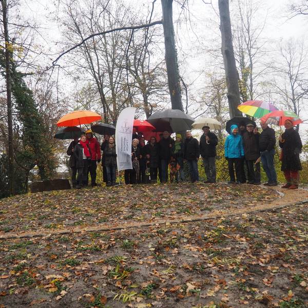 Eine Gruppe Menschen steht auf einem Hügel, auf den ein spiralförmig gewundener Weg führt.