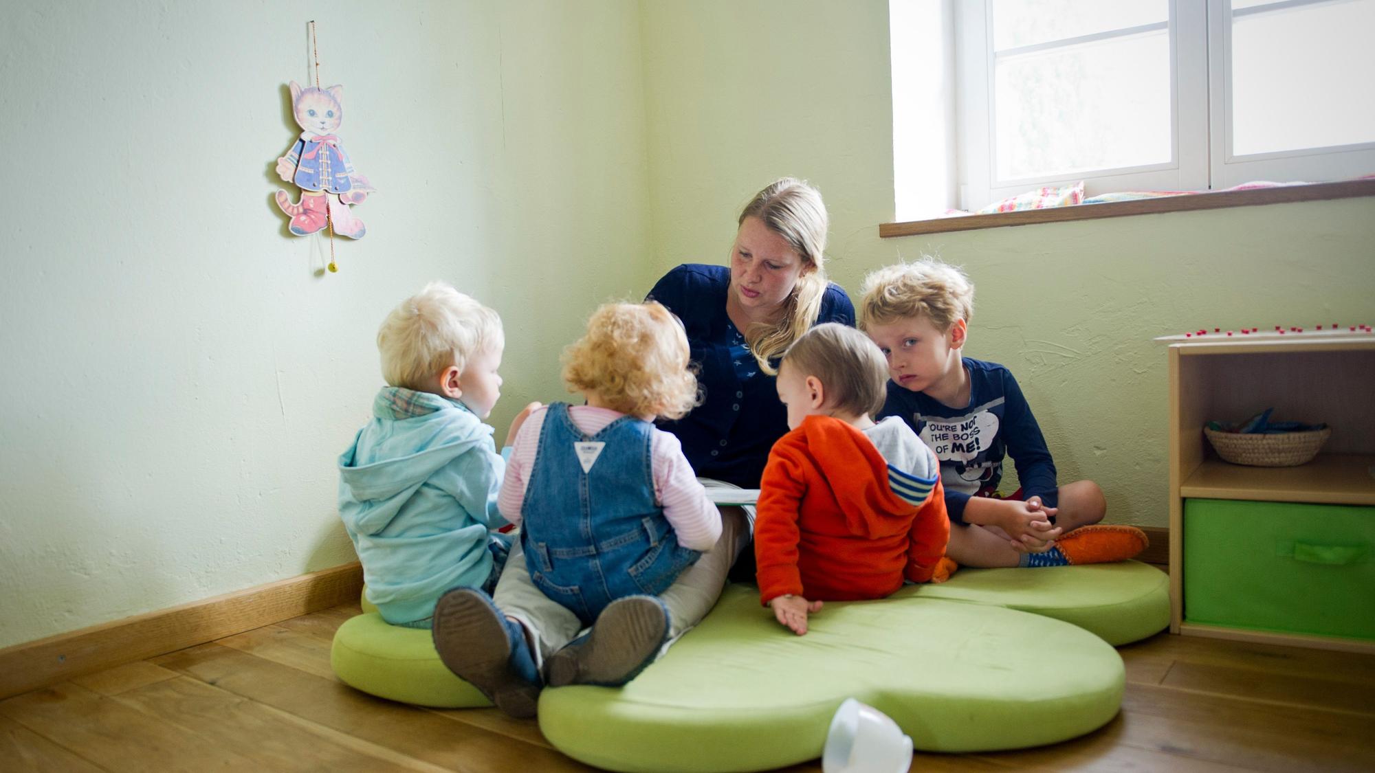 Kinder sitzen vor einer Erzieherin.