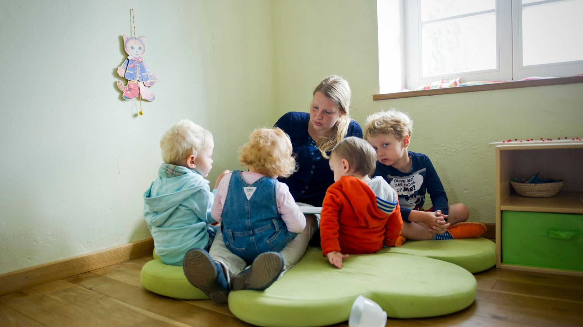 Kinder sitzen vor einer Erzieherin.