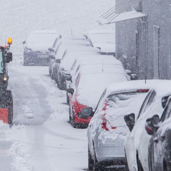 Ein Schneeräumfahrzeug im Einsatz auf einer verschneiten Straße.