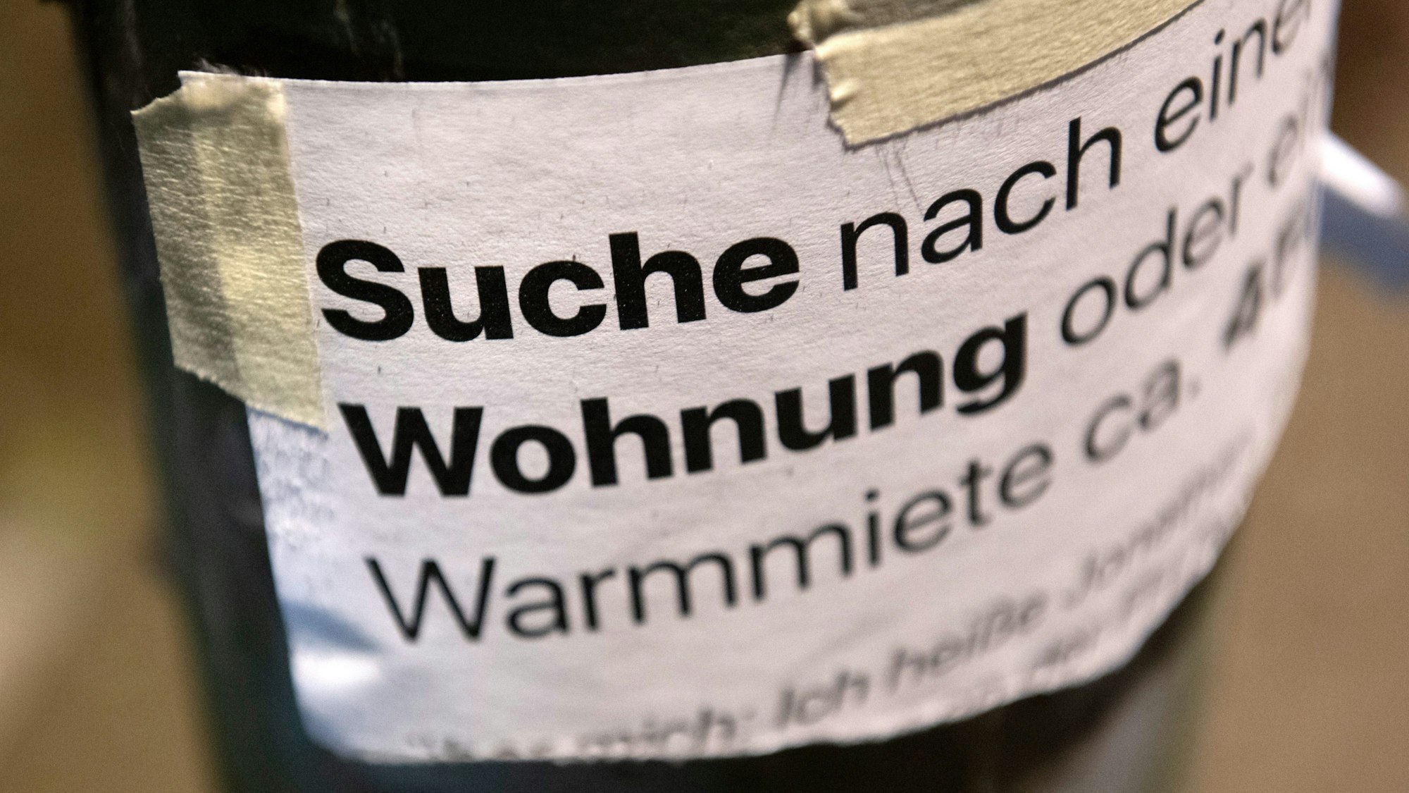„Suche Wohnung“ steht auf einem Zettel an einer Laterne.
