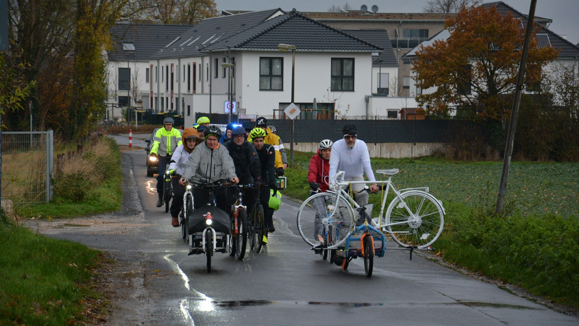 Fahrräder fahren über einen Feldweg, einer transportiert ein weißes Geisterfahrrad.