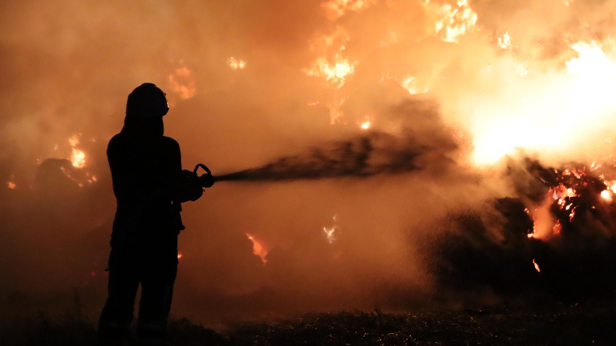 Das Bild zeigt einen Feuerwehrmann, der vor einer Feuerwand steht.
