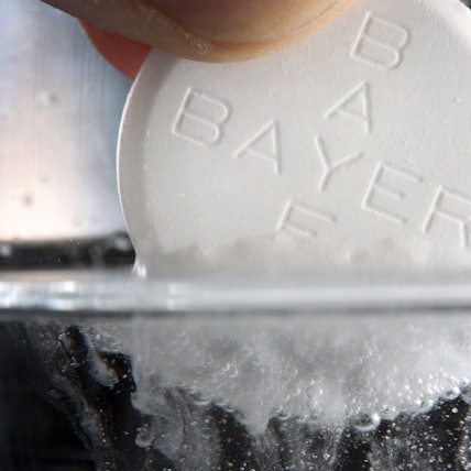 Eine Aspirin-Tablette des Bayer-Konzerns löst sich in einem Wasserglas auf.
