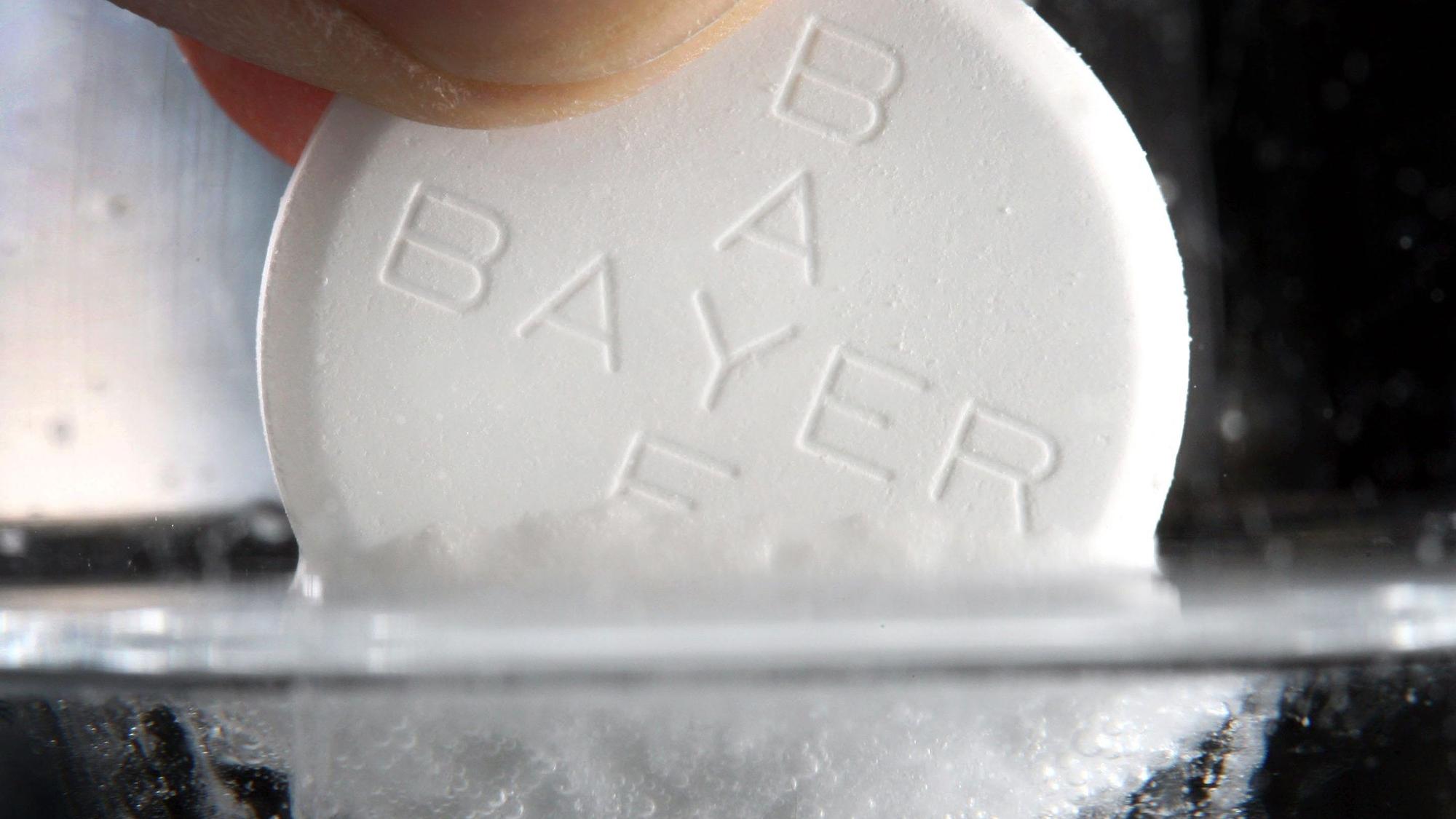 Eine Aspirin-Tablette des Bayer-Konzerns löst sich in einem Wasserglas auf.