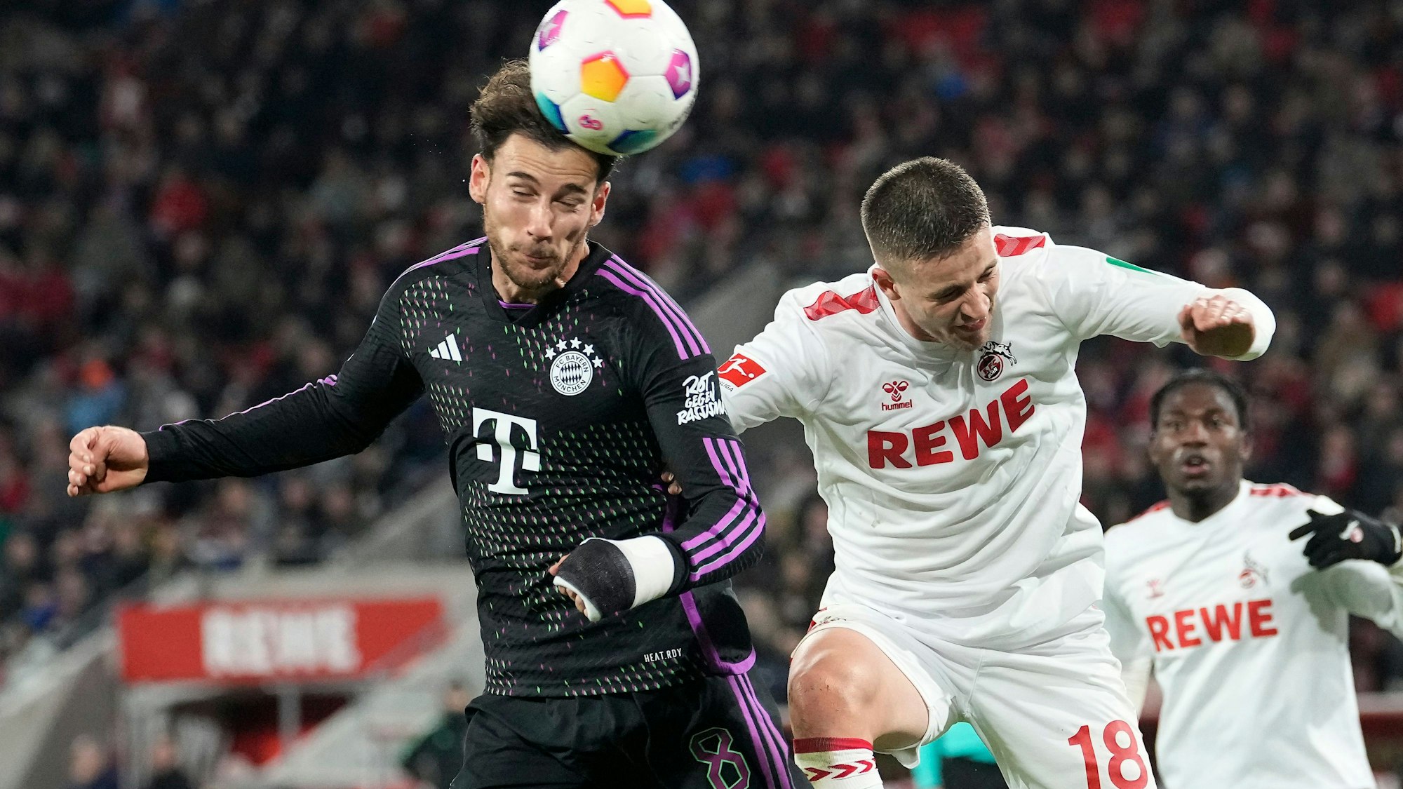 Kölns Rasmus Carstensen (r.)und Münchens Leon Goretzka springen zum Kopfball-Duell hoch.