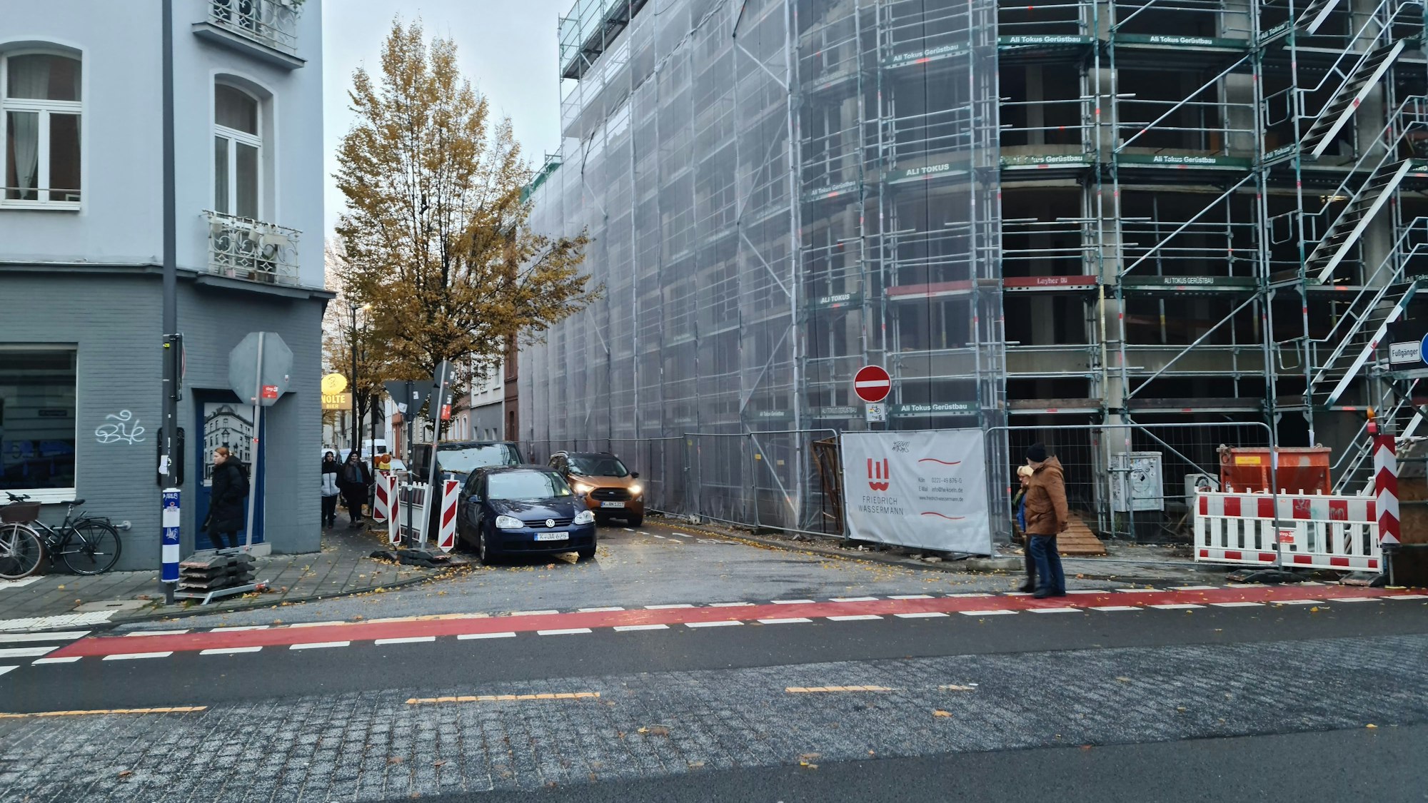 Die Einmündung einer schmalen Straße auf eine größere ist zu sehen. An der Ecke ist die Baustelle eines mehrstöckigen Hauses.