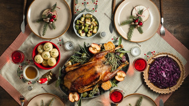 Symbolbild: Ein traditionelles deutsches Weihnachtsessen mit Gans, Rotkohl und Klößen auf einem festlich gedeckten Tisch.
