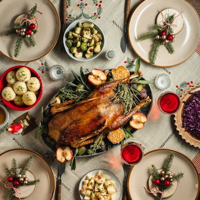 Symbolbild: Ein traditionelles deutsches Weihnachtsessen mit Gans, Rotkohl und Klößen auf einem festlich gedeckten Tisch.