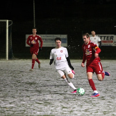 Ein Dahlemer Fußballer ist auf dem Schnee schneller als sein Frauenberger Gegenspieler.