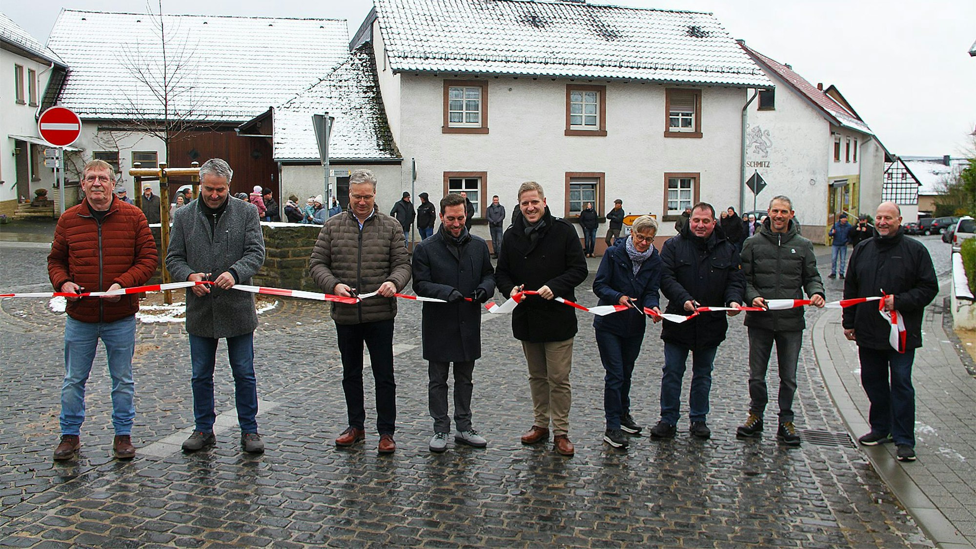 Vertreter aus Kreis, Gemeinde und Versorgern halten ein rot-weißes Flatterband in den Händen, das sie durchschneiden.