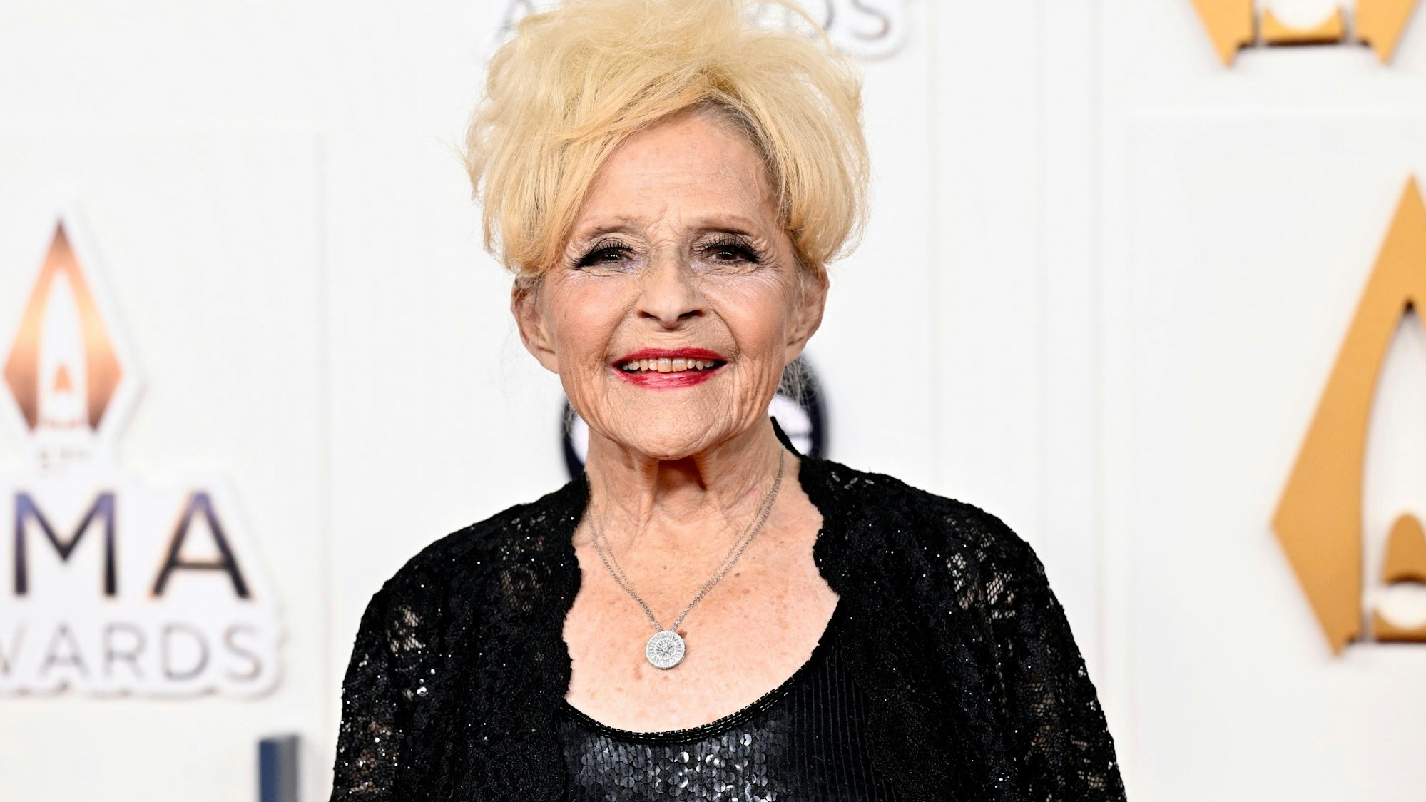 Brenda Lee trägt ihre blonden Haare hochgesteckt und ein schwarzes Abendkleid.