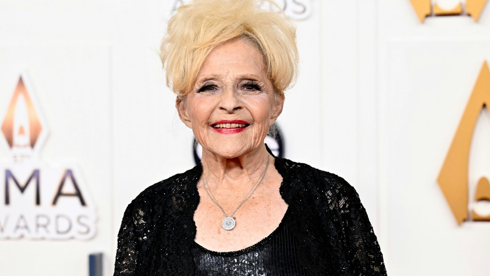 Brenda Lee trägt ihre blonden Haare hochgesteckt und ein schwarzes Abendkleid.