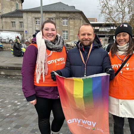 Ein Mann und zwei Frauen mit einer Regenbogenfahne