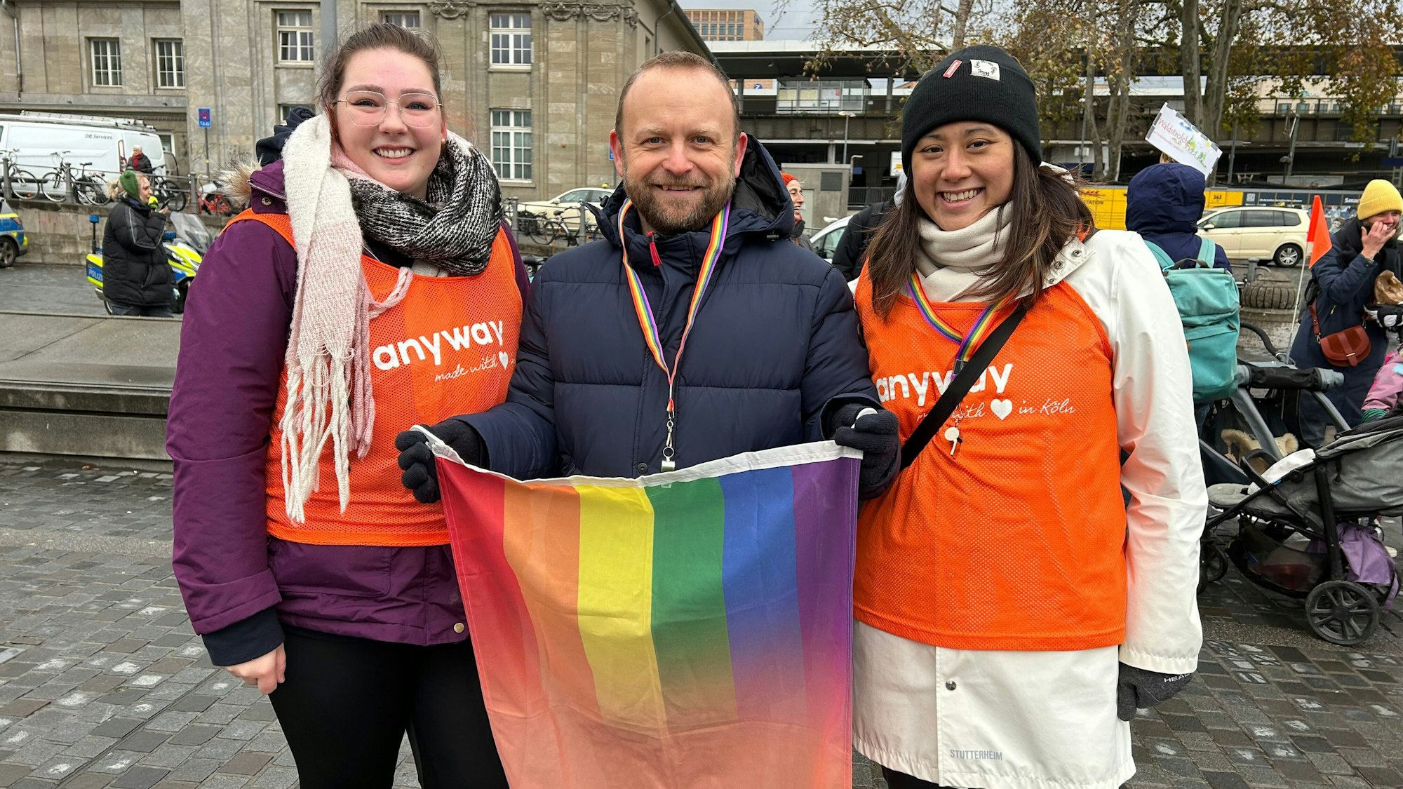 Ein Mann und zwei Frauen mit einer Regenbogenfahne