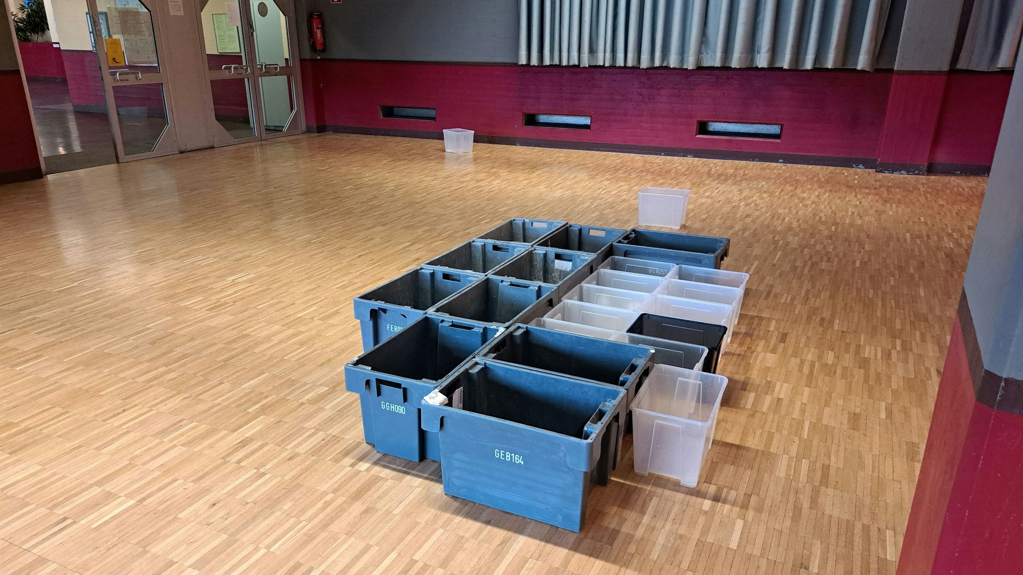 Auf dem Parkettboden der Aula des Niederkasseler Kopernikus-Gymnasiums stehen Plastikbehälter, die das durch die Decke eindringende Regenwasser auffangen.