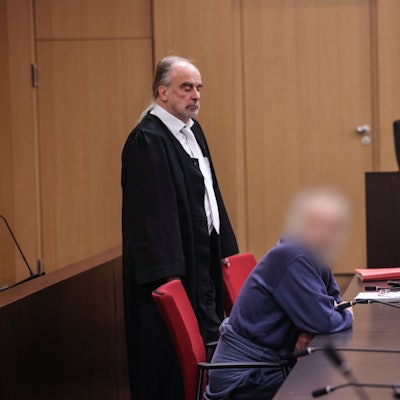 Der Angeklagte sitzt im Gerichtssaal neben seinem Anwalt Frank Schubert auf der Anklagebank. Wegen einer verheerenden Explosion in einem Hochhaus in Ratingen muss sich ein 57 Jahre alter Deutscher vor dem Landgericht Düsseldorf verantworten. Bei der Explosion vor sechs Monaten wurden mehrere Einsatzkräfte von Polizei, Feuerwehr und Rettungsdienst zum Teil schwer verletzt.