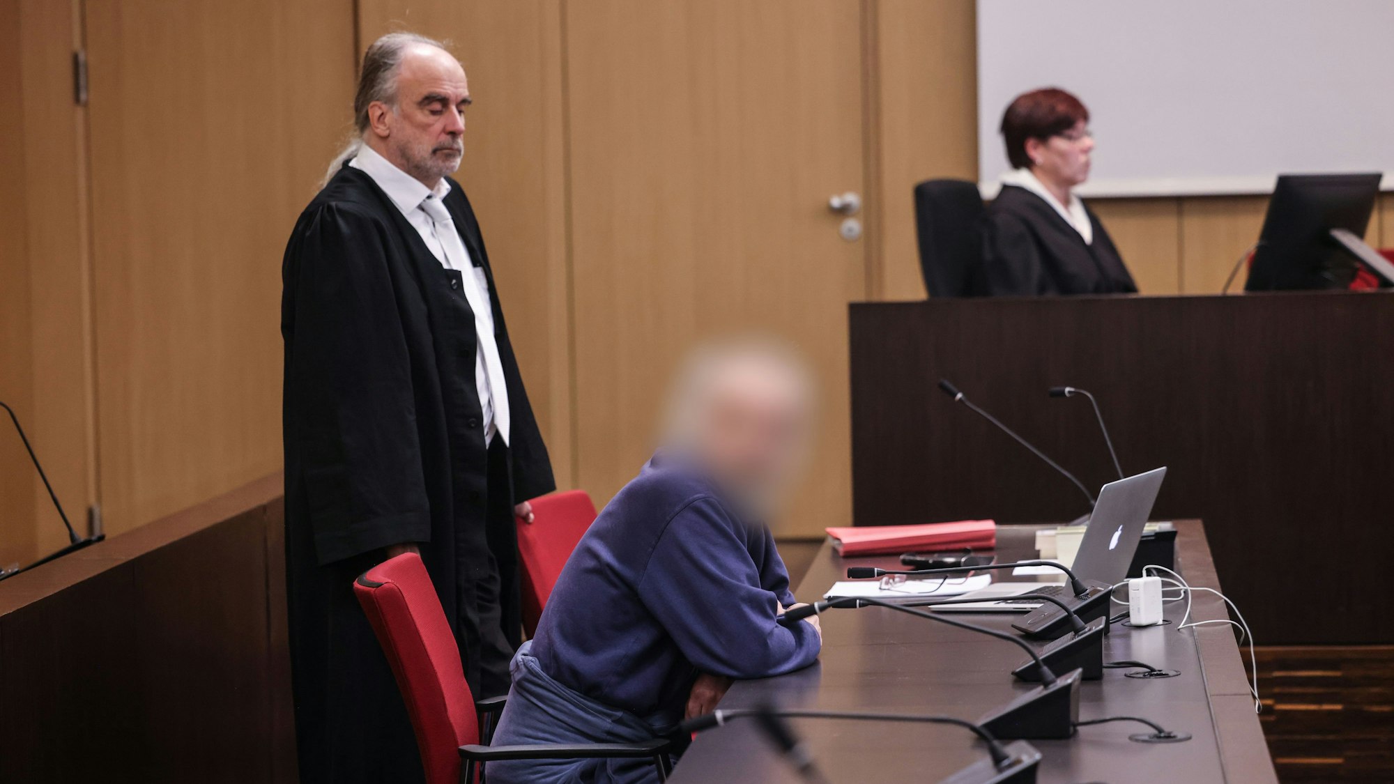 Der Angeklagte (M) sitzt im Gerichtssaal neben seinem Anwalt Frank Schubert (M) auf der Anklagebank. Wegen einer verheerenden Explosion in einem Hochhaus in Ratingen muss sich ein 57 Jahre alter Deutscher vor dem Landgericht Düsseldorf verantworten. Bei der Explosion vor sechs Monaten wurden mehrere Einsatzkräfte von Polizei, Feuerwehr und Rettungsdienst zum Teil schwer verletzt.