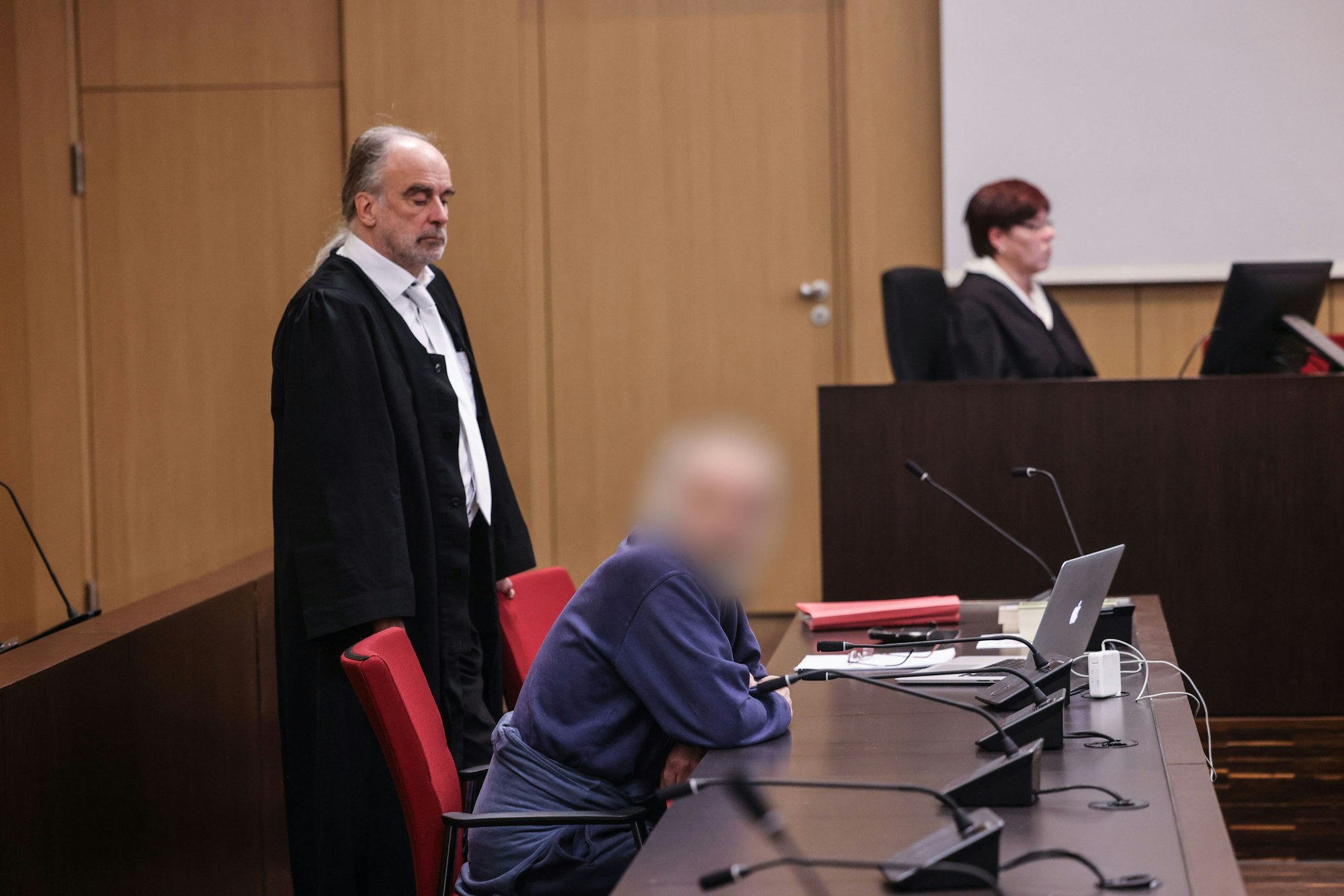 Der Angeklagte sitzt im Gerichtssaal neben seinem Anwalt Frank Schubert auf der Anklagebank. Wegen einer verheerenden Explosion in einem Hochhaus in Ratingen muss sich ein 57 Jahre alter Deutscher vor dem Landgericht Düsseldorf verantworten. Bei der Explosion vor sechs Monaten wurden mehrere Einsatzkräfte von Polizei, Feuerwehr und Rettungsdienst zum Teil schwer verletzt.