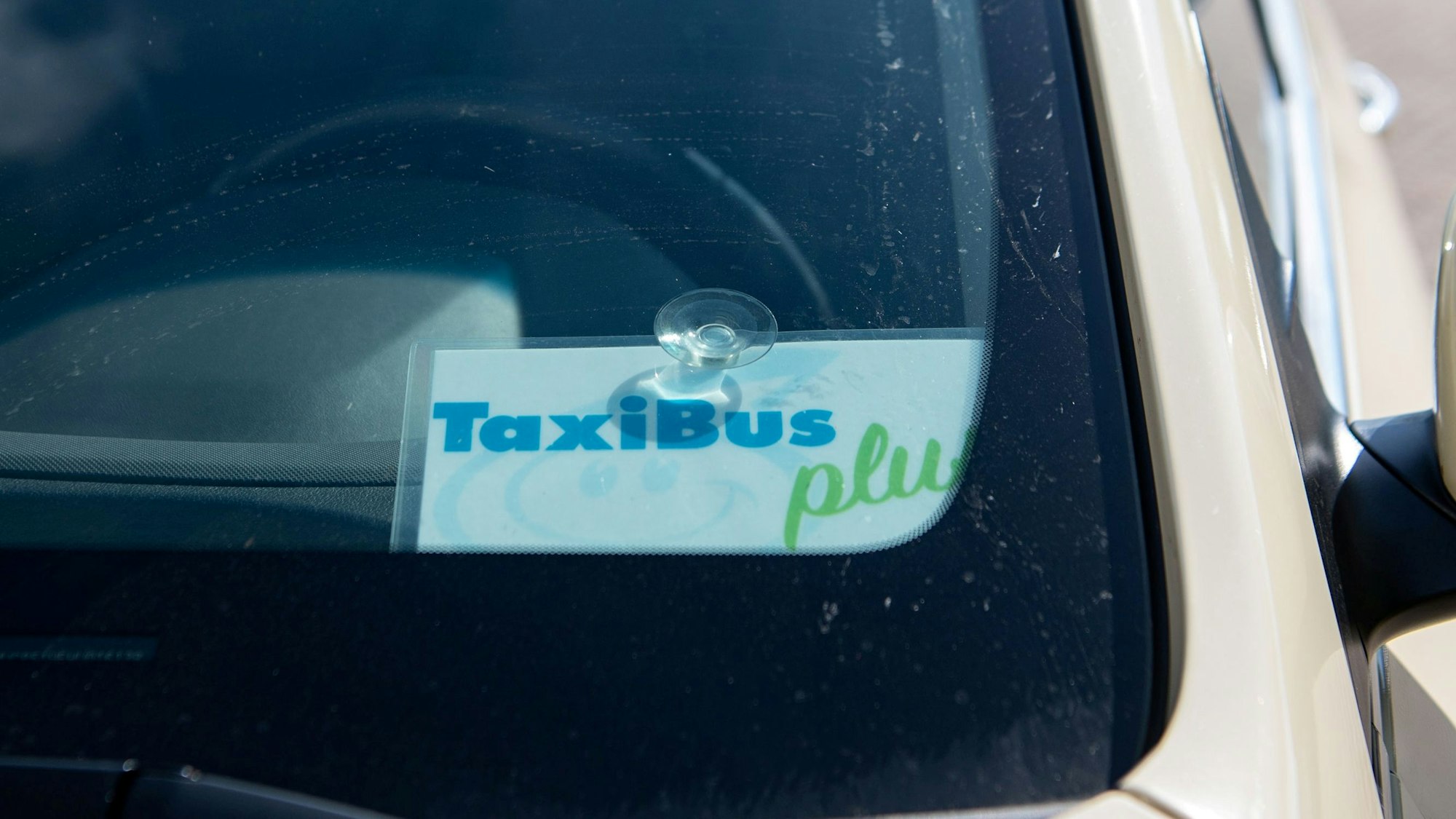 Ein Schild mit der Aufschrift Taxi-Bus-Plus hängt in einem Taxi.