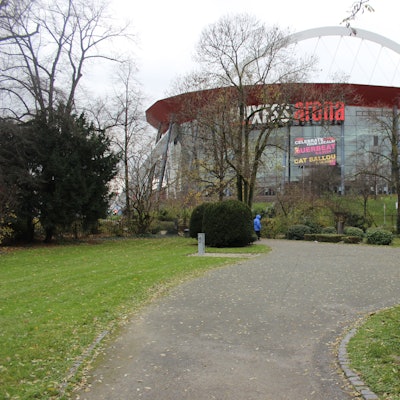 Parkanlage, im Hintergrund ein großes Glasgebäude