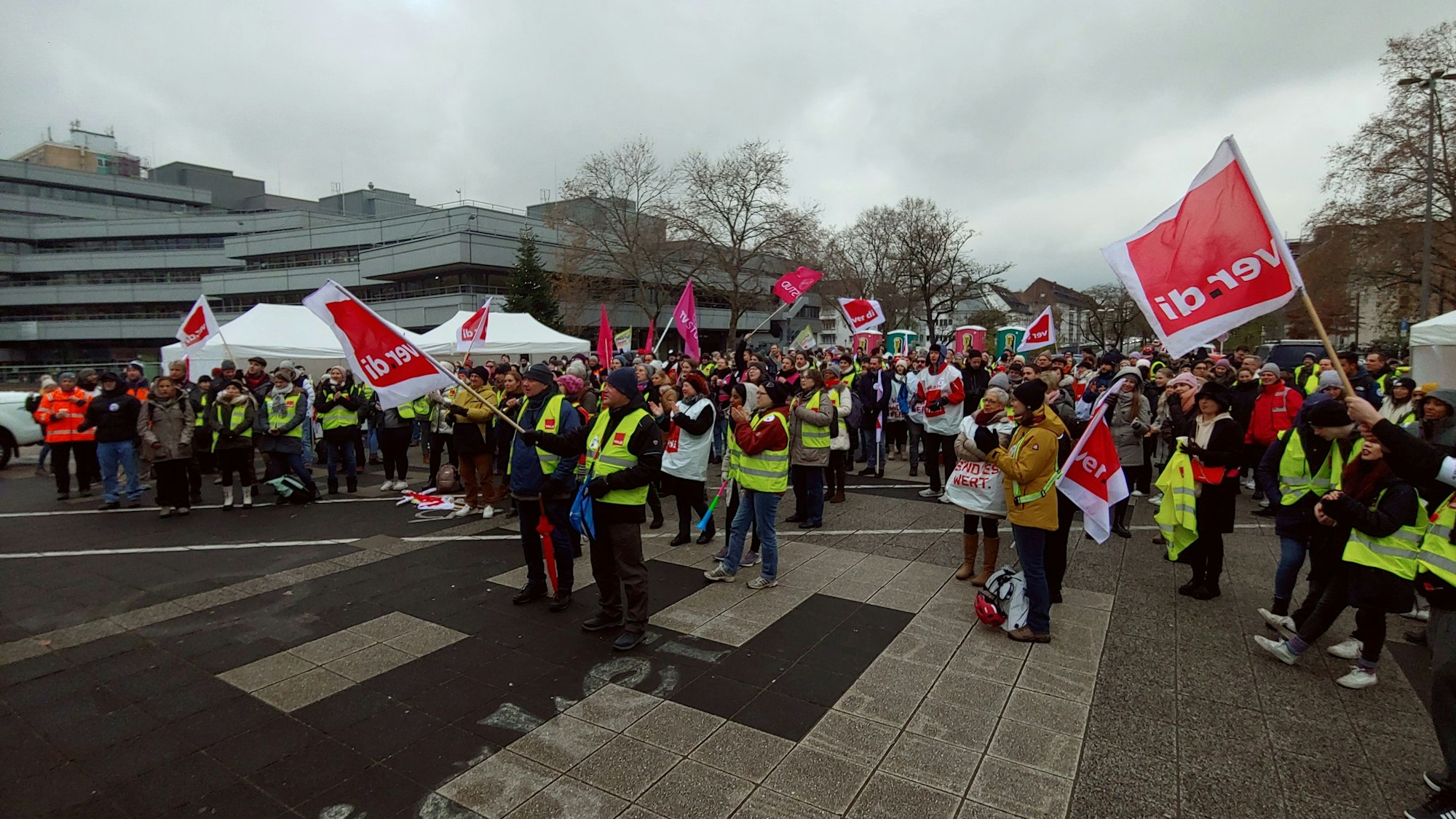 Menschen, die mit Verdi-Fahnen und in gelben Warnwesten demonstrieren.