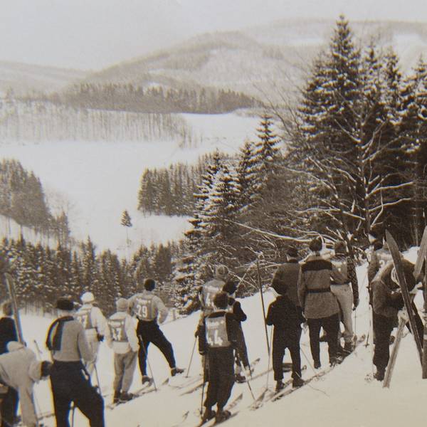 Skifahrer am Hang mit Nummernleibchen.