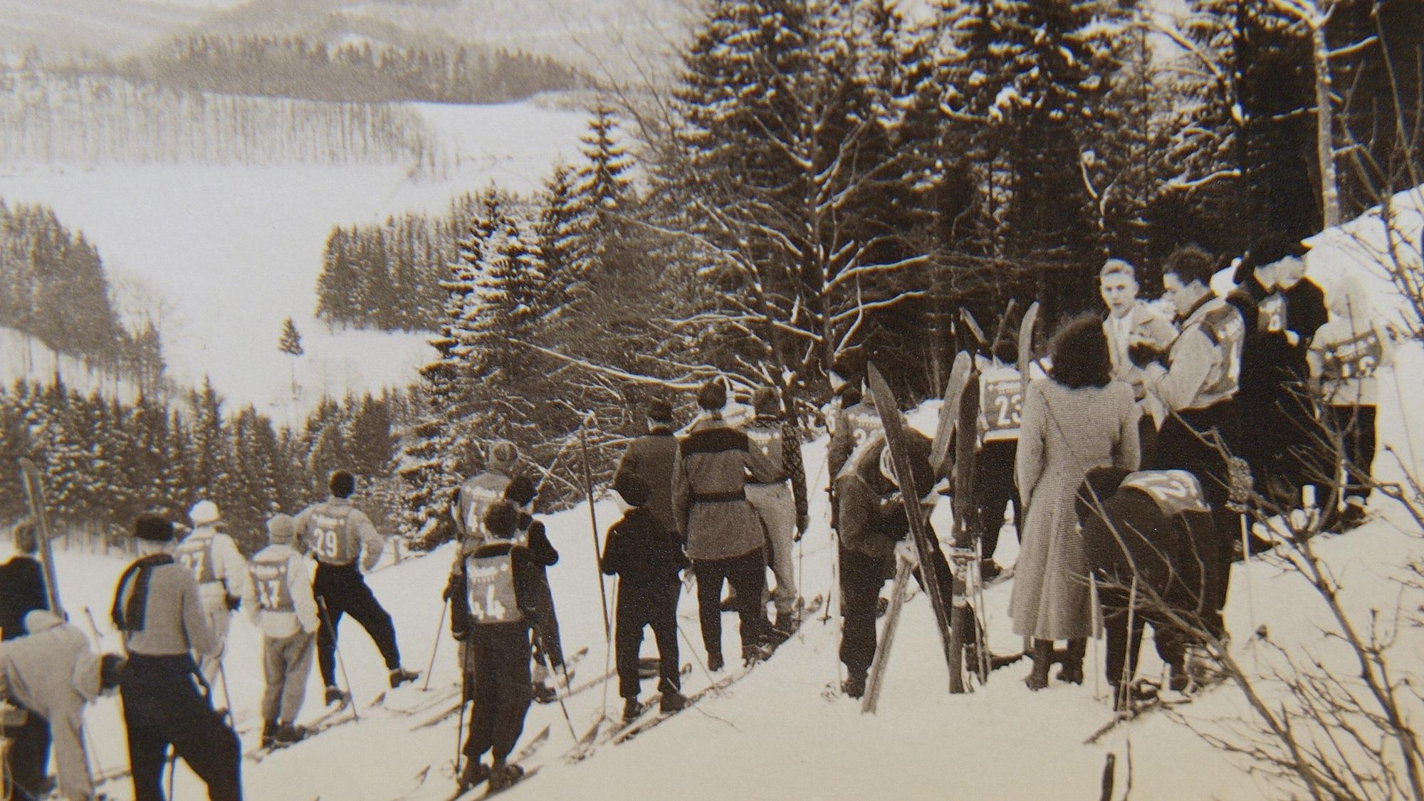 Skifahrer am Hang mit Nummernleibchen.