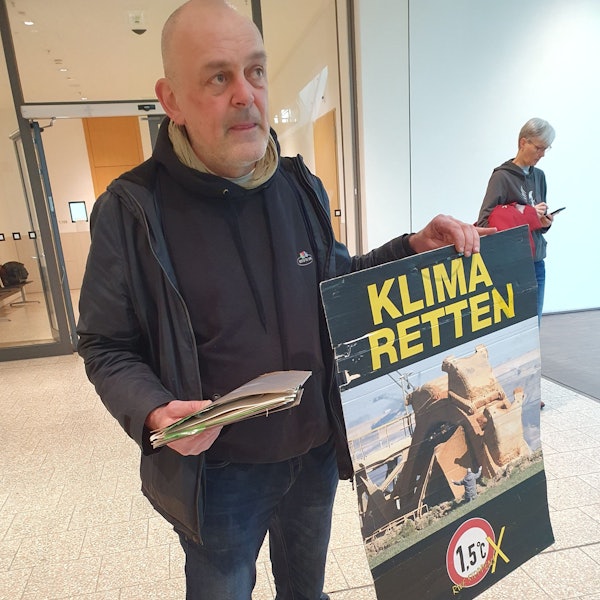 Winfried Bernhardt, Klimaaktivist, steht mit einem Plakat mit der Aufschrift «Klima retten» im Foyer des Gerichts. Wegen einer Attacke mit Kartoffelbrei im NRW-Landtag musste er sich vor Gericht verantworten. Die Staatsanwaltschaft warf ihm Sachbeschädigung vor.