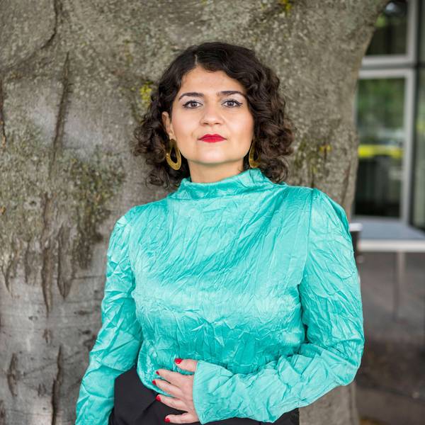 Die Regisseurin Pınar Karabulut posiert vor einem Baumstamm. Sie trägt eine türkis-schimmernde Bluse.