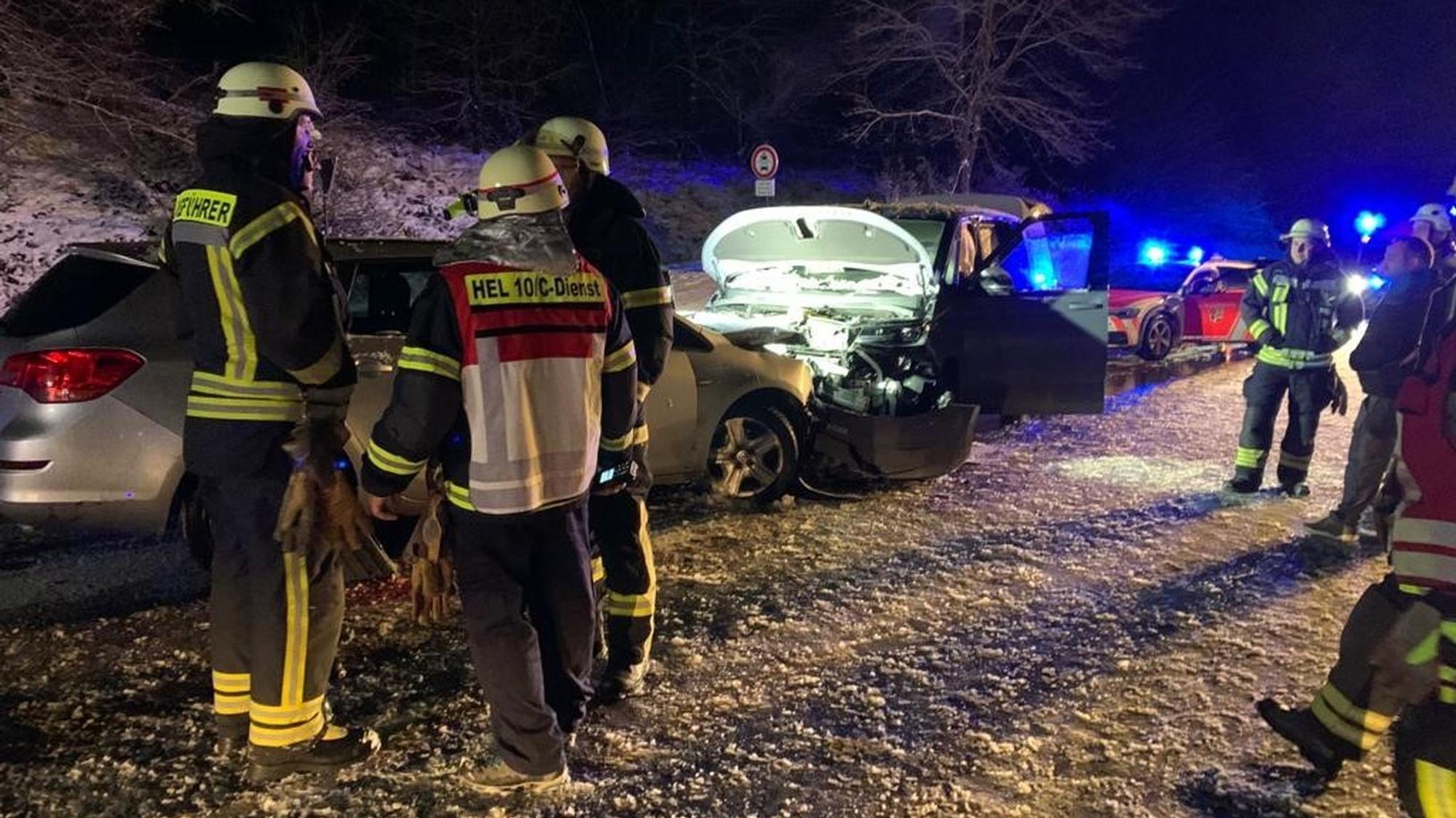 Feuerwehrleute aus Hellenthal an den beiden zusammengestoßenen Fahrzeugen. Die Straße ist total vereist.