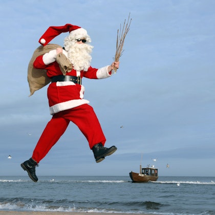 Ein Mann im Weihnachtsmannkostüm vor Meereskulisse.