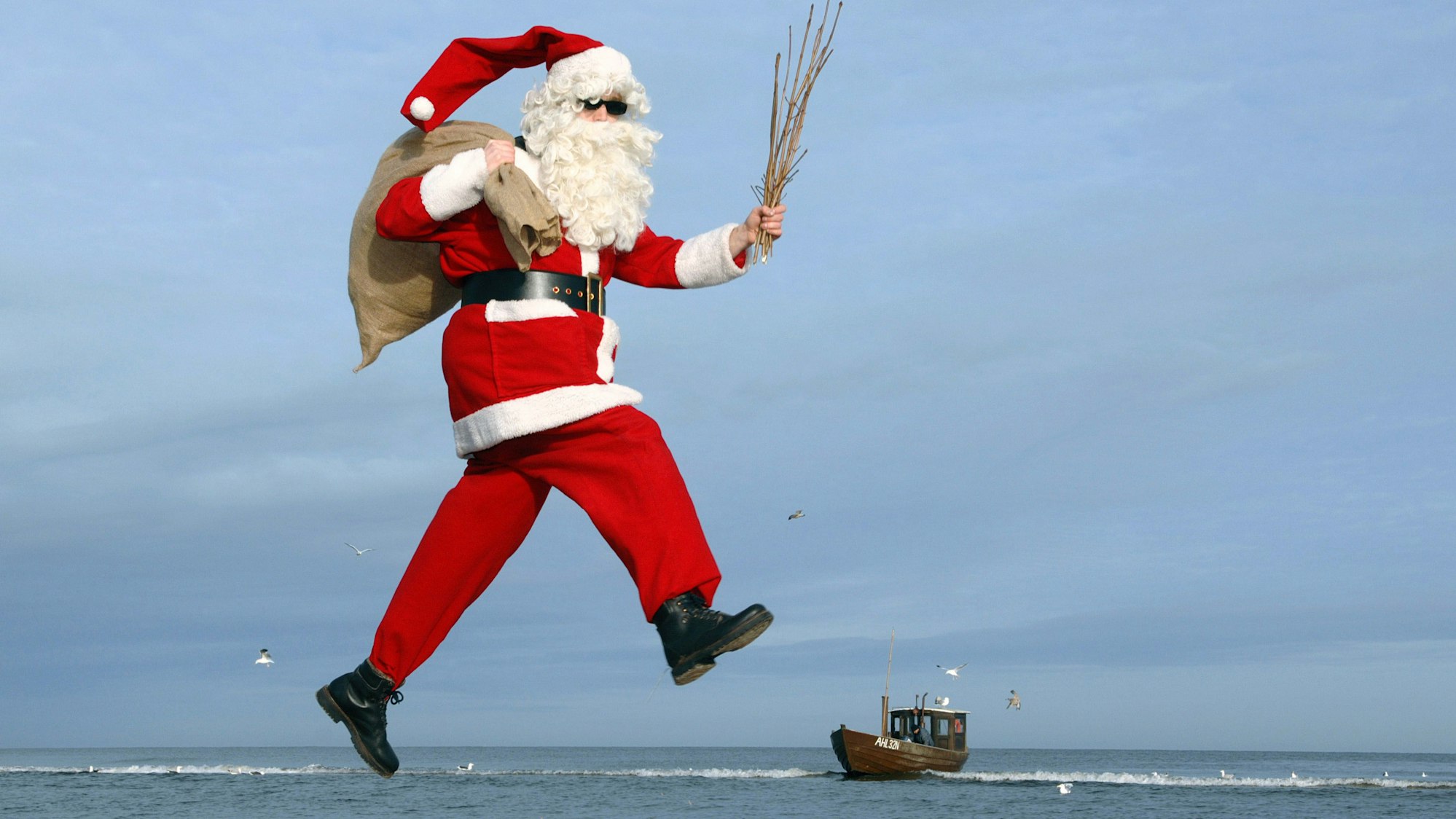 Ein Mann im Weihnachtsmannkostüm vor Meereskulisse.