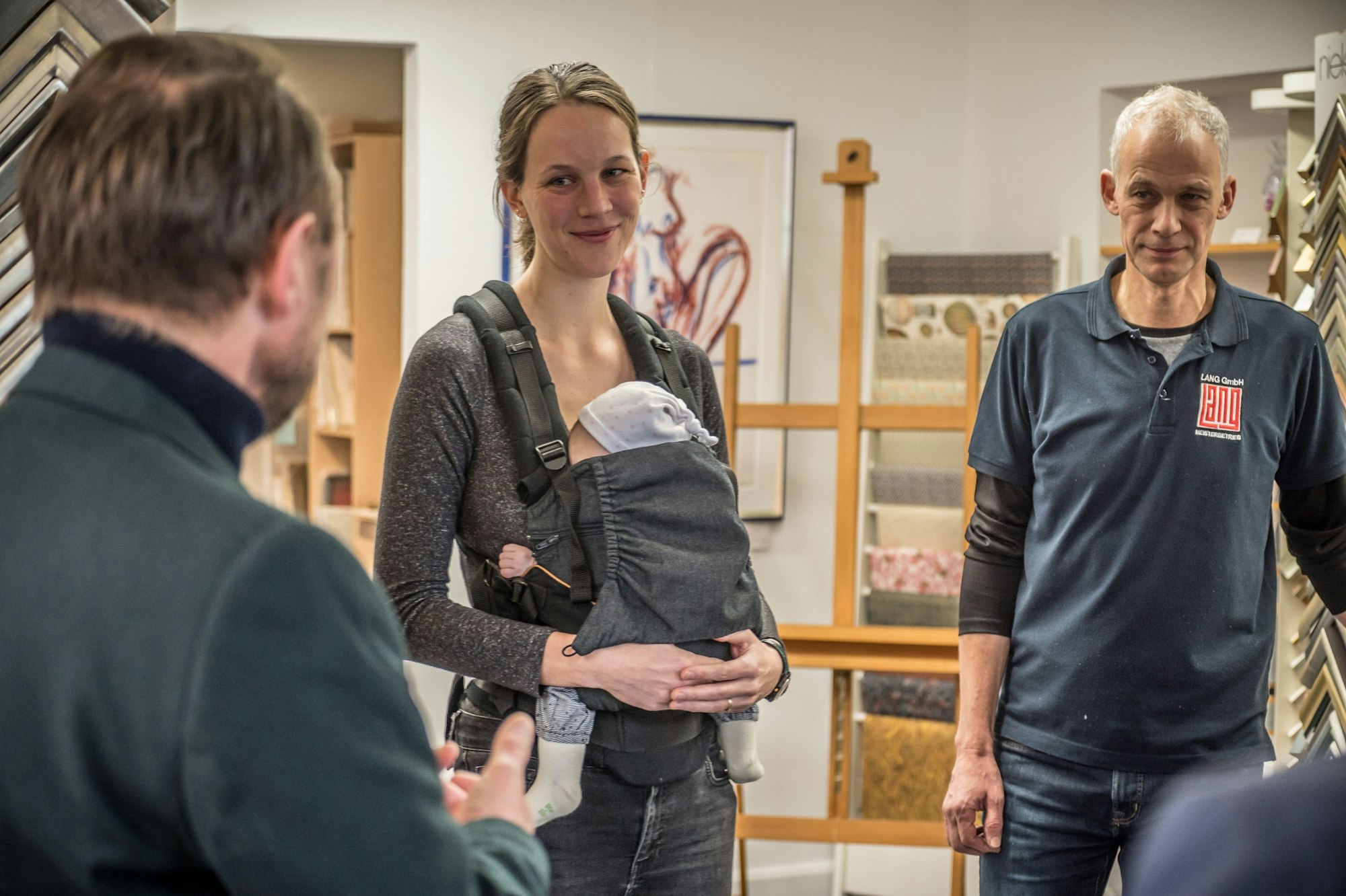 Katrin Böttcher mit Baby und ihrem Vater Frank Lang im Verkaufsraum der Buchbinderei Lang an der Lichstraße.