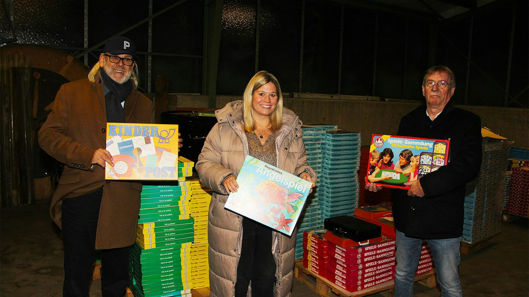 Bernd Pfennings,  Bürgermeisterin Jennifer Meuren und ihr Allgemeiner Vertreter Erwin Nelles stehen vor großen Stapeln von Brettspielen.