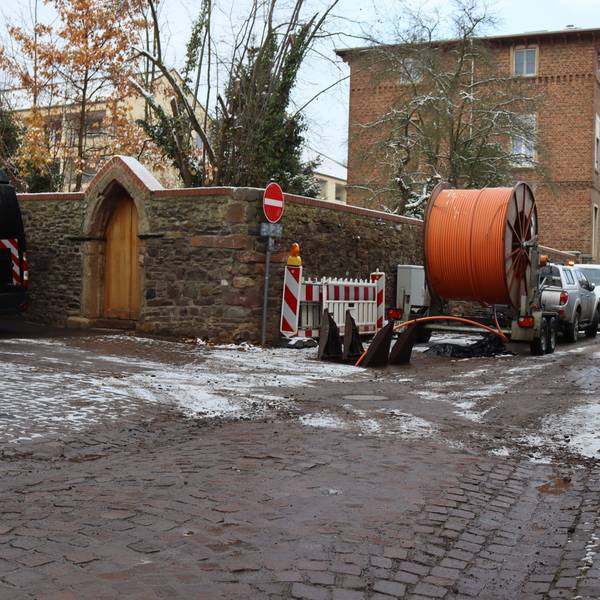 Auf der Alten Gasse in Bad Münstereifel wird zwischen Kapuzinergasse und Wallgasse derzeit gearbeitet. Ein Anhänger mit Kabeln steht an der Seite.