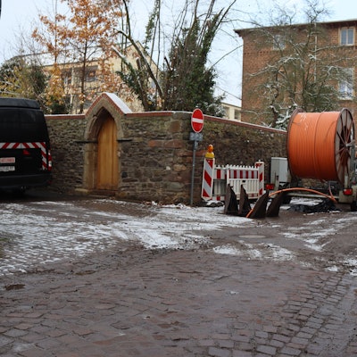 Auf der Alten Gasse in Bad Münstereifel wird zwischen Kapuzinergasse und Wallgasse derzeit gearbeitet. Ein Anhänger mit Kabeln steht an der Seite.
