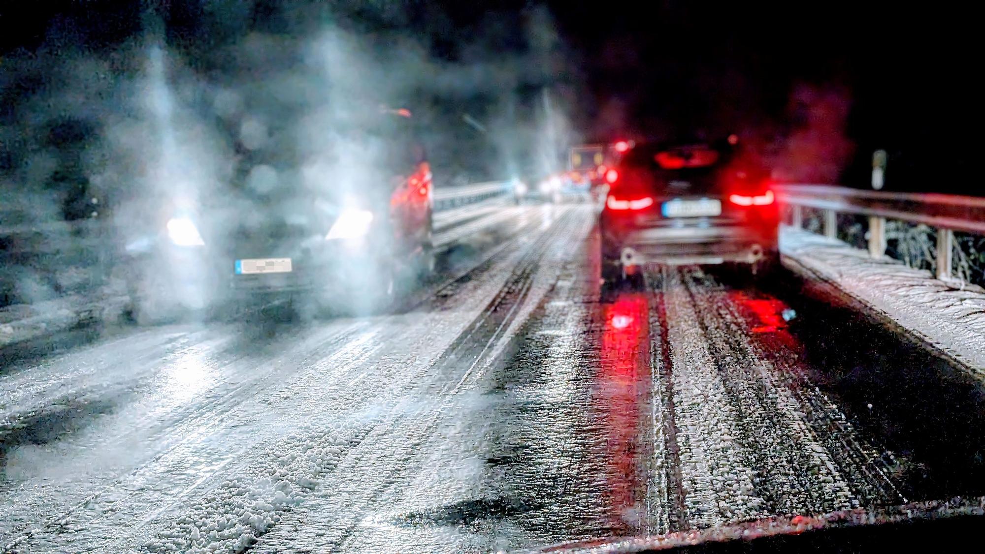 Auf einer Landstraße im Kreis Euskirchen fahren mehrere Autos bei Nacht über eine vereiste Straße. Am Straßenrand liegt Schnee. (Archivbild)