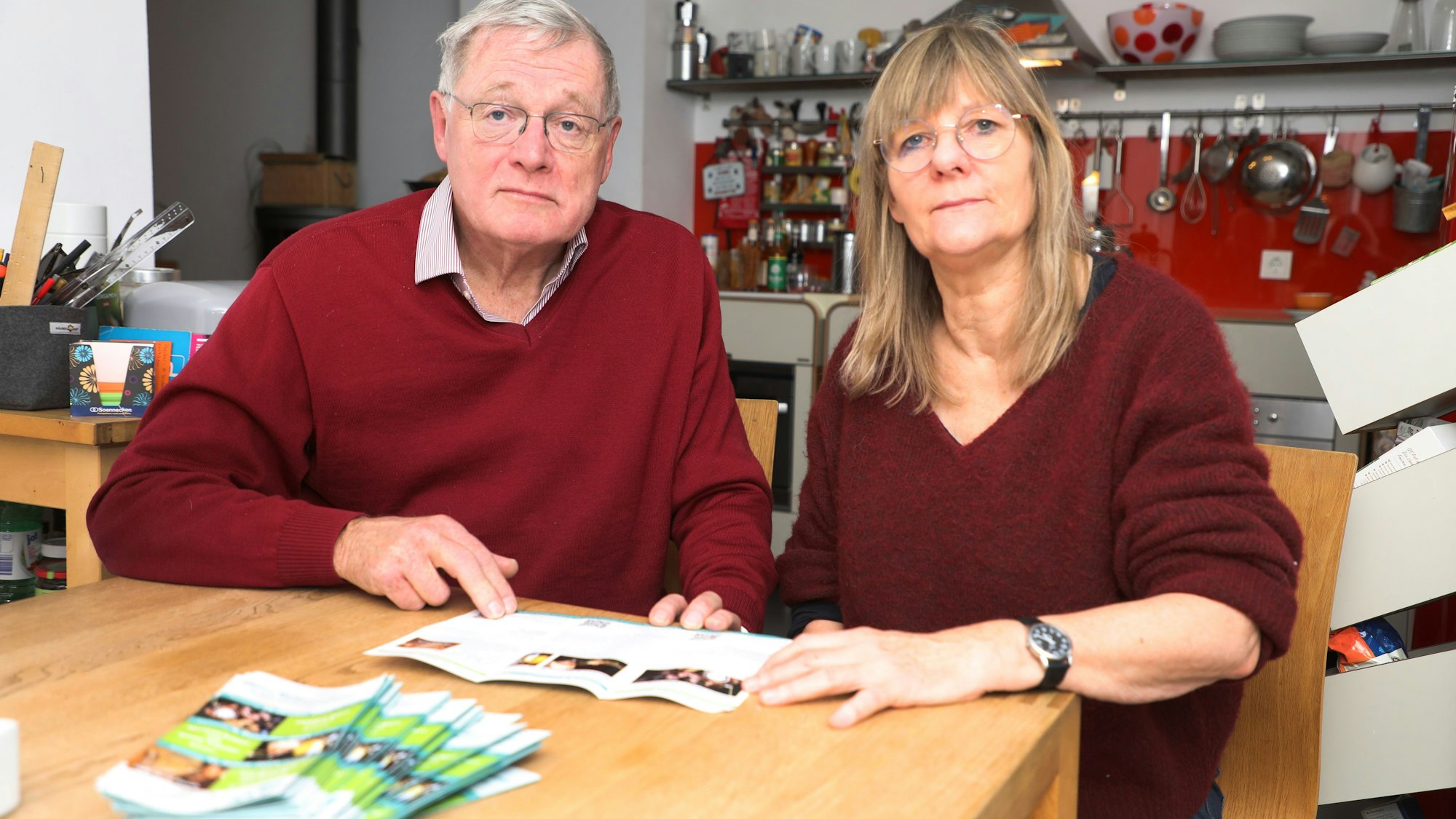 Der Vorsitzende des Kulturforums Overath, Jürgen Wesche, und Vize-Vorsitzende Margret Altemeier sitzen mit sorgenvoller Miene an einem Tisch und halten das Programm des Kulturforums in den Händen.