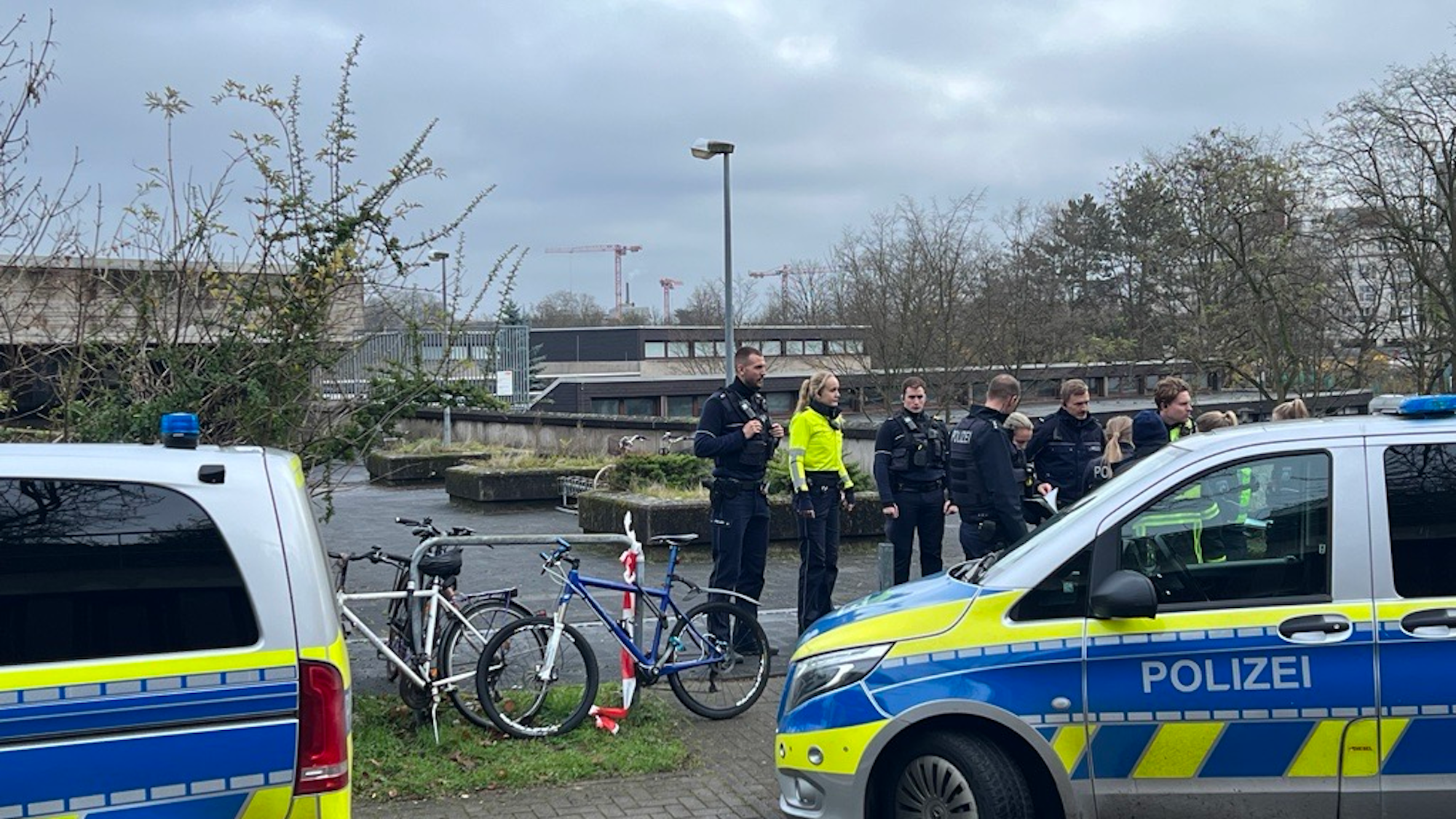 Einsatzwagen und Einsatzkräfte der Polizei vor einem Schulgebäude in Köln-Müngersdorf.