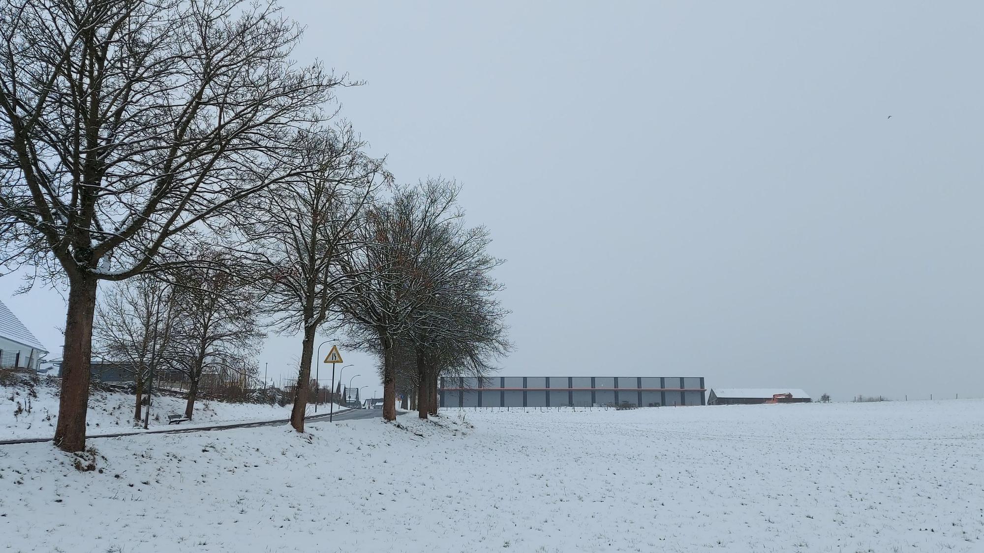 Gezeigt wird ein verschneiter Acker, am linken Bildrand befinden sich Häuser.