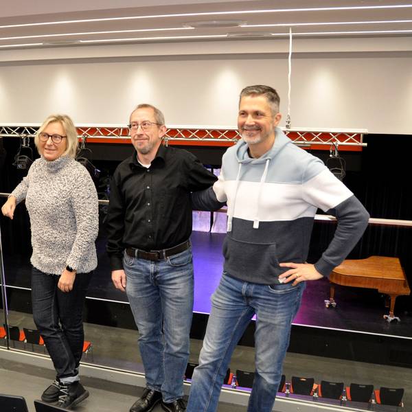 Zwei Frauen und zwei Männer stehen auf der Empore einer Aula.