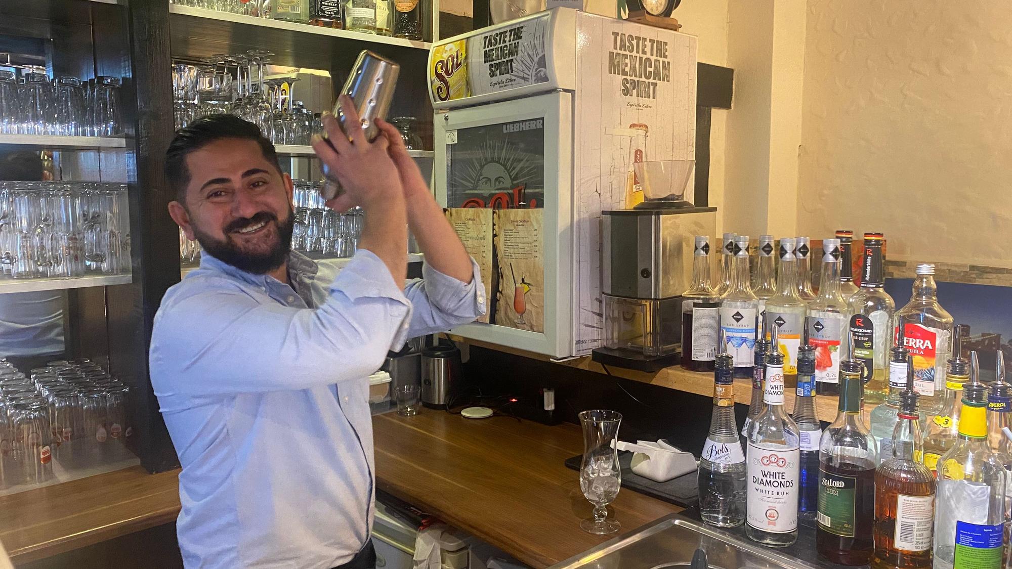 Ein Mann steht hinter einer Bar und mixt einen Cocktail