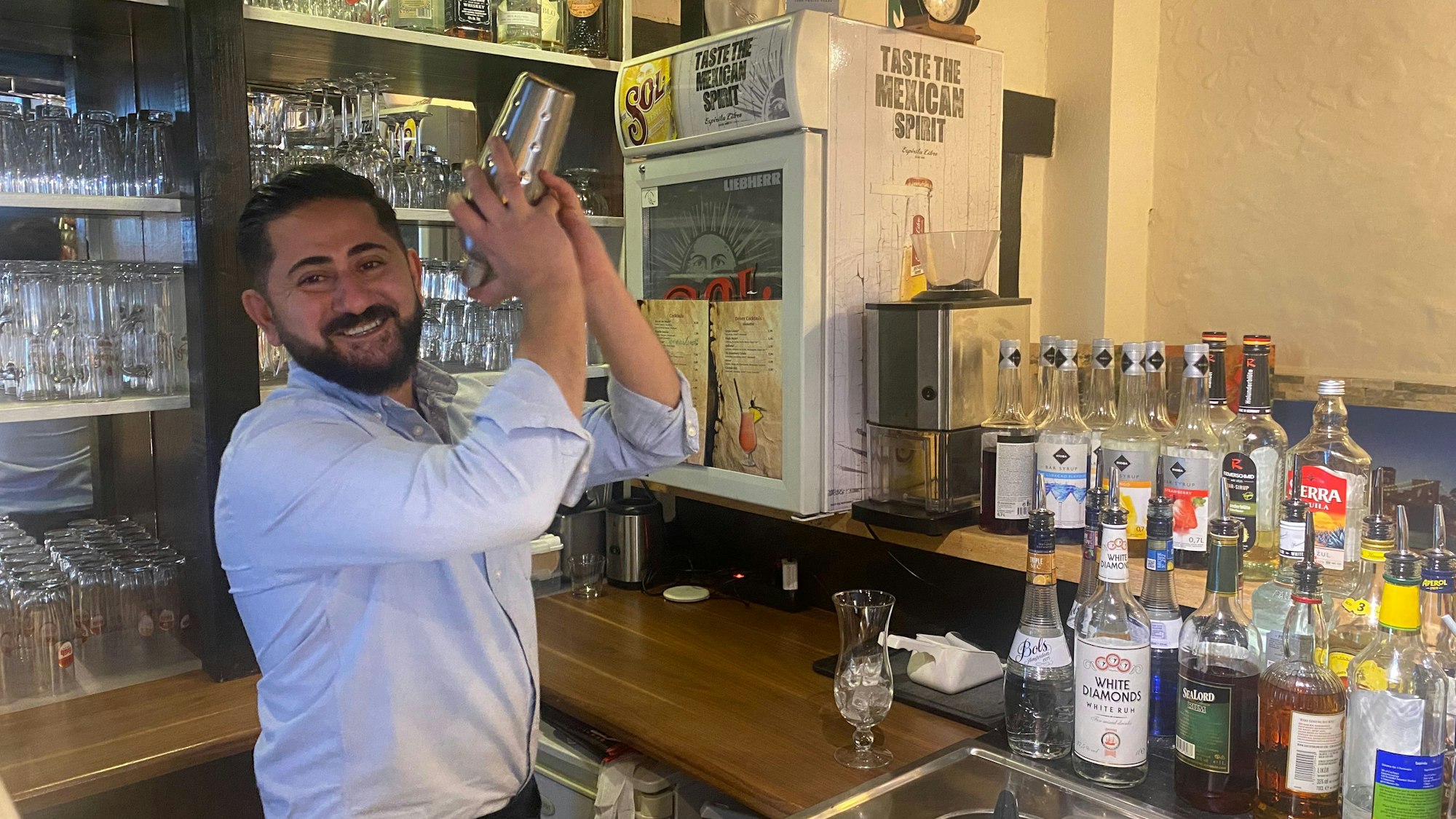 Ein Mann steht hinter einer Bar und mixt einen Cocktail